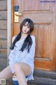 A woman sitting on the steps of a wooden door.