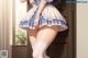 A woman in a blue and white dress and stockings posing for a picture.