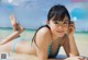 A woman in a blue and white bikini laying on the beach.