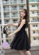 A woman in a black dress standing on a balcony.