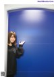 A woman standing in front of a blue wall with a sign that says Bay FM 78.