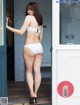 A woman in a white bikini standing in front of a door.