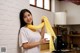 A woman holding a yellow scarf in a kitchen.